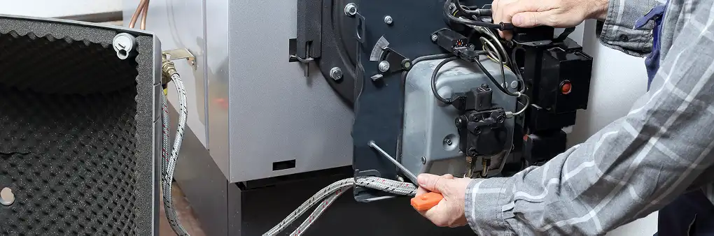 Techniker arbeitet an einer Ölheizung im Heizungskeller