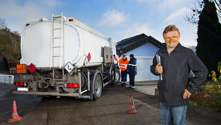 Im Vordergrund ein Mann mit Brille. Im Hintergrund ein Heizöl-Tankwagen mit zwei Personen und eine Garage